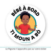 Ce sticker rond présente une illustration colorée d’un petit garçon noir avec des cheveux bouclés et volumineux (cheveux afro enfant). Il porte un t-shirt rouge uni et tient un moulin à vent multicolore dans sa main droite. Le texte "Bébé à bord" est affiché en haut, tandis que "Ti Moun A Bò", en créole Antillais Guyanais, est inscrit en bas en noir. Le texte "Clairatier" est situé au bas du sticker. Sticker bébé à bord.