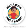 Ce sticker rond représente un petit garçon noir avec des cheveux bouclés tombant en mèches sur son front. Il porte un t-shirt rouge uni et tient un moulin à vent multicolore dans sa main droite. Le texte "Bébé à Bord" est inscrit en haut, tandis que "Bebê a Bordo", en portugais (langue parlée dans des pays comme le Brésil, le Portugal ou encore le Cap-Vert), apparaît en bas dans une police noire audacieuse. Sticker bebê a bordo. 